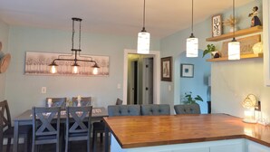 A dining area with a wooden table, grey upholstered chairs, and pendant lighting.