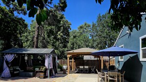 A patio area with stone flooring, a covered seating area, and a blue umbrella.