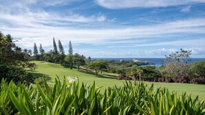 A lush green golf course with a clear view of the ocean and a resort in the distance. - 🏖️Ocean View Condo + Pickleball | Top Floor w/ AC (Kailua Kona)