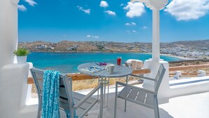 Una terrazza con vista sul paesaggio costiero, un tavolo con una bevanda e un paio di occhiali da sole.