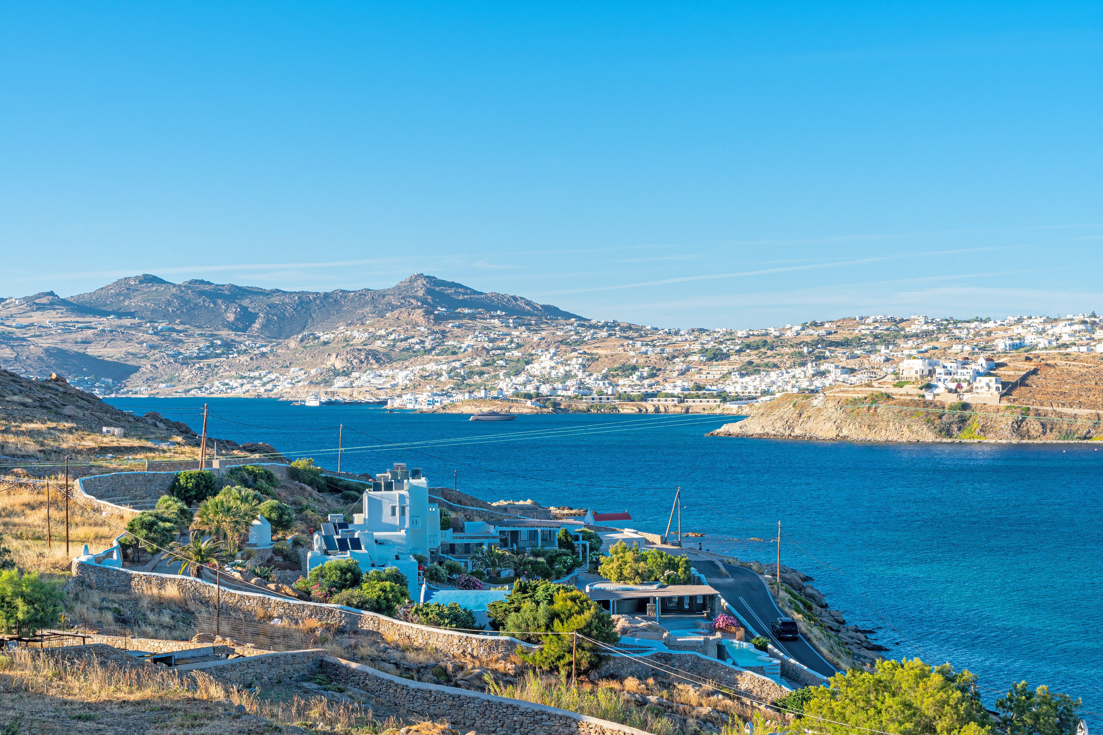 A coastal town with a prominent view of the sea, a winding road, and a mix of residential and commercial buildings.