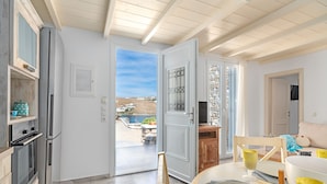 Una cucina moderna con forno a incasso e frigorifero, una porta aperta che dà su un balcone con vista sul paesaggio.