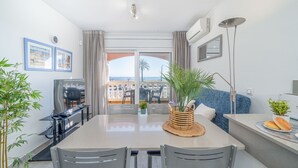 A modern dining area with a large table, chairs, and a view of the sea through glass doors. - 0022-BAHIA Apartment in front of the beach with wifi (Empuriabrava)