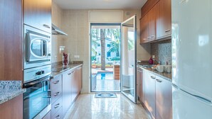 Une cuisine moderne dotée d’appareils électroménagers en acier inoxydable, de meubles en bois et offrant une vue sur l’extérieur.