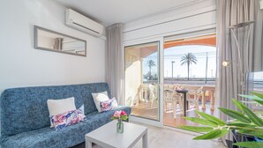A modern living room with a blue sofa, a white coffee table, and a view of an outdoor patio with a table and chairs. - 0017-BAHIA Apartment in front of the beach with wifi (Empuriabrava)