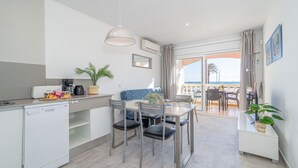 A modern kitchen with a dishwasher, dining table with chairs, and a balcony with a view of the sea. - 0020-BAHIA Apartment in front of the beach with wifi (Empuriabrava)