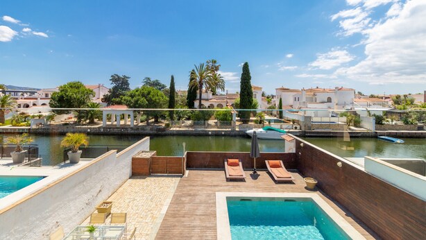 A rooftop pool area with lounge chairs, a small pool, and a view of the cityscape and water. - 0106-LLOBREGAT House at the canal with pool and mooring (Empuriabrava)