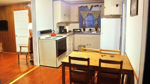 Una cocina funcional con estufa, lavamanos y mesa de comedor de madera.
