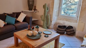 A living room with a brown sofa, a wooden coffee table, a cactus, and a window with a view of trees. - Exceptional riverside estate 48 pers swimming pool private beaches (La roque sur ceze)