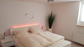 A bedroom with a bed, bedside tables, a potted plant, and wall art. - Lounge 1 - Top apartment approx. 75sqm, parking at the house, all in (Koblenz)