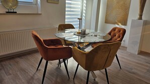 A dining area with a glass table, four chairs, a decorative piece on the wall, and a radiator. - Lounge 1 - Top apartment approx. 75sqm, parking at the house, all in (Koblenz)
