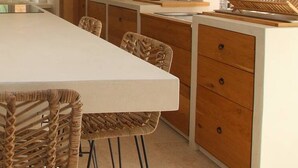 A long dining table with wicker chairs, a white countertop, and wooden cabinets. - Your splendid stone farmhouse in the countryside, completely renovated (Cabris)
