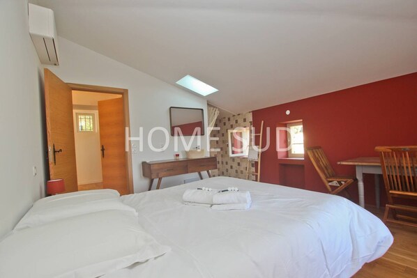 Un dormitorio con cama, escritorio, silla y ventana.