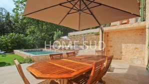 An outdoor patio with a wooden table and chairs, a large umbrella, and a stone wall. - Your splendid stone farmhouse in the countryside, completely renovated (Cabris)