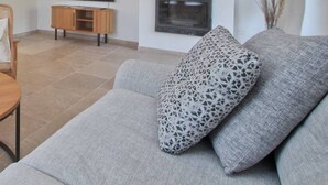 A modern living room with a round wooden table, a grey sofa, and wicker chairs. - Your splendid stone farmhouse in the countryside, completely renovated (Cabris)