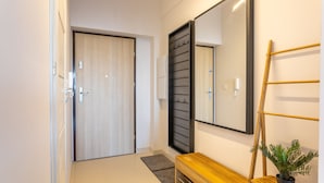 Un corridoio con una porta in legno, una panca, uno specchio e una pianta.