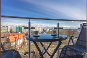 Ein Balkon mit Tisch und Stühlen, der einen Blick auf die Stadt mit Gebäuden und einem Kran bietet.