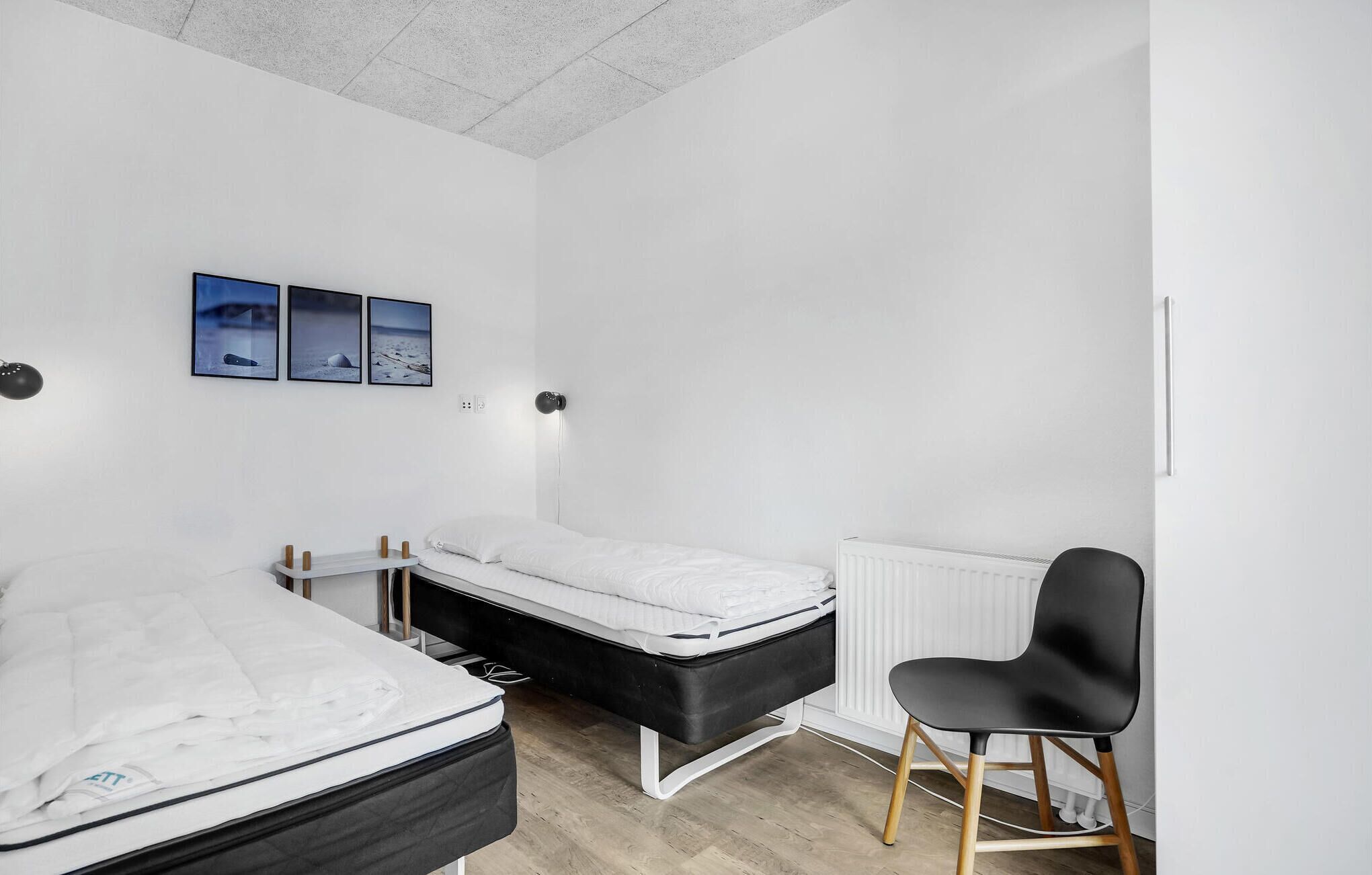 A minimalist bedroom with a bed, a desk, and a chair.