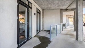 Ein Korridor aus Beton mit Glastüren, einem Metallgeländer und einer sichtbaren Wasserrand auf dem Boden.