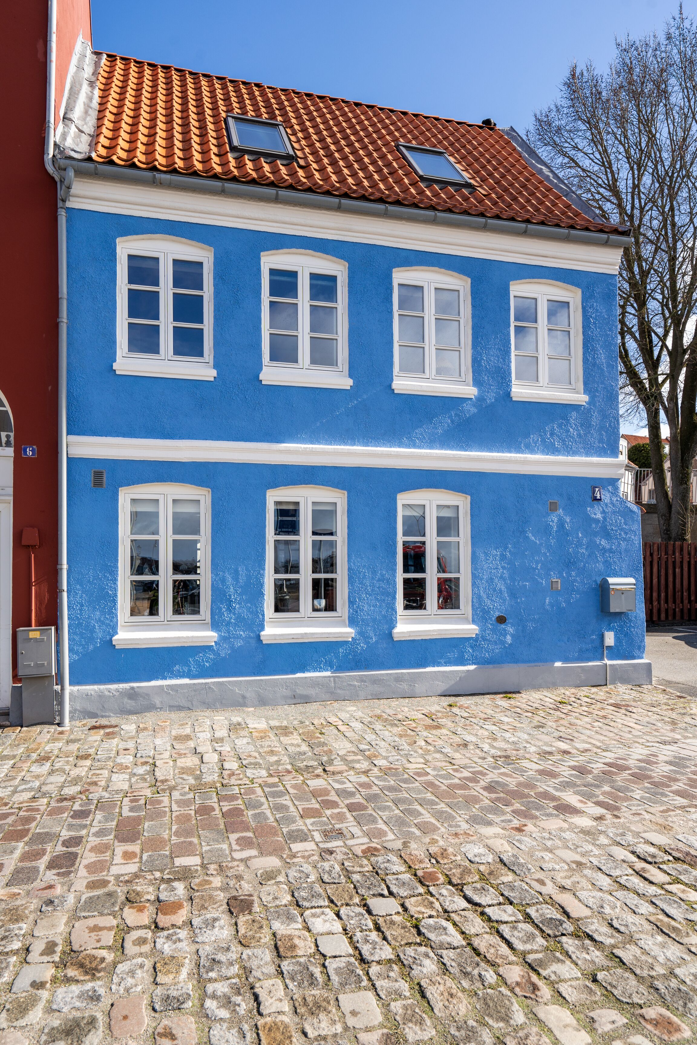 Ein zweistöckiges Gebäude mit blauer Fassade und weißen Fensterrahmen.