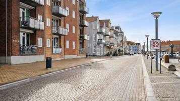 Una calle adoquinada flanqueada por edificios residenciales de varios pisos, una señal de límite de velocidad y un farol.