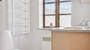A bathroom with a toilet, a window, and a sink.