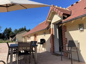 Una veranda esterna con tavolo e sedie, un barbecue e una zona coperta.