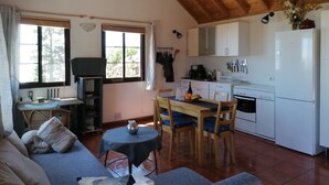 A cozy living area with a sofa, a dining table, and a kitchen with white cabinets and a Bosch refrigerator. - Casa Monte for astro and nature lovers (Puntagorda)
