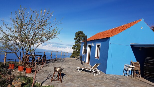 A blue building with a tiled roof, outdoor seating, and a view of the sea. - Casa Monte for astro and nature lovers (Puntagorda)