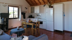 A cozy kitchen with wooden beams, a dining table with chairs, and a refrigerator. - Casa Monte for astro and nature lovers (Puntagorda)