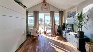 A spacious room with a wooden floor, a cozy chair, a dining table, and a kitchen area with cabinets and a stove. - Amazing home in Vänersnäs with WiFi (Vänersnäs)