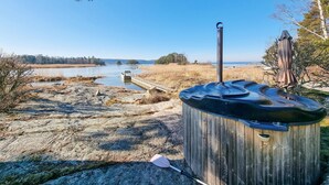 A wooden sauna with a metal chimney, a paddle, and a wooden dock extending into a lake. - Amazing home in Vänersnäs with WiFi (Vänersnäs)