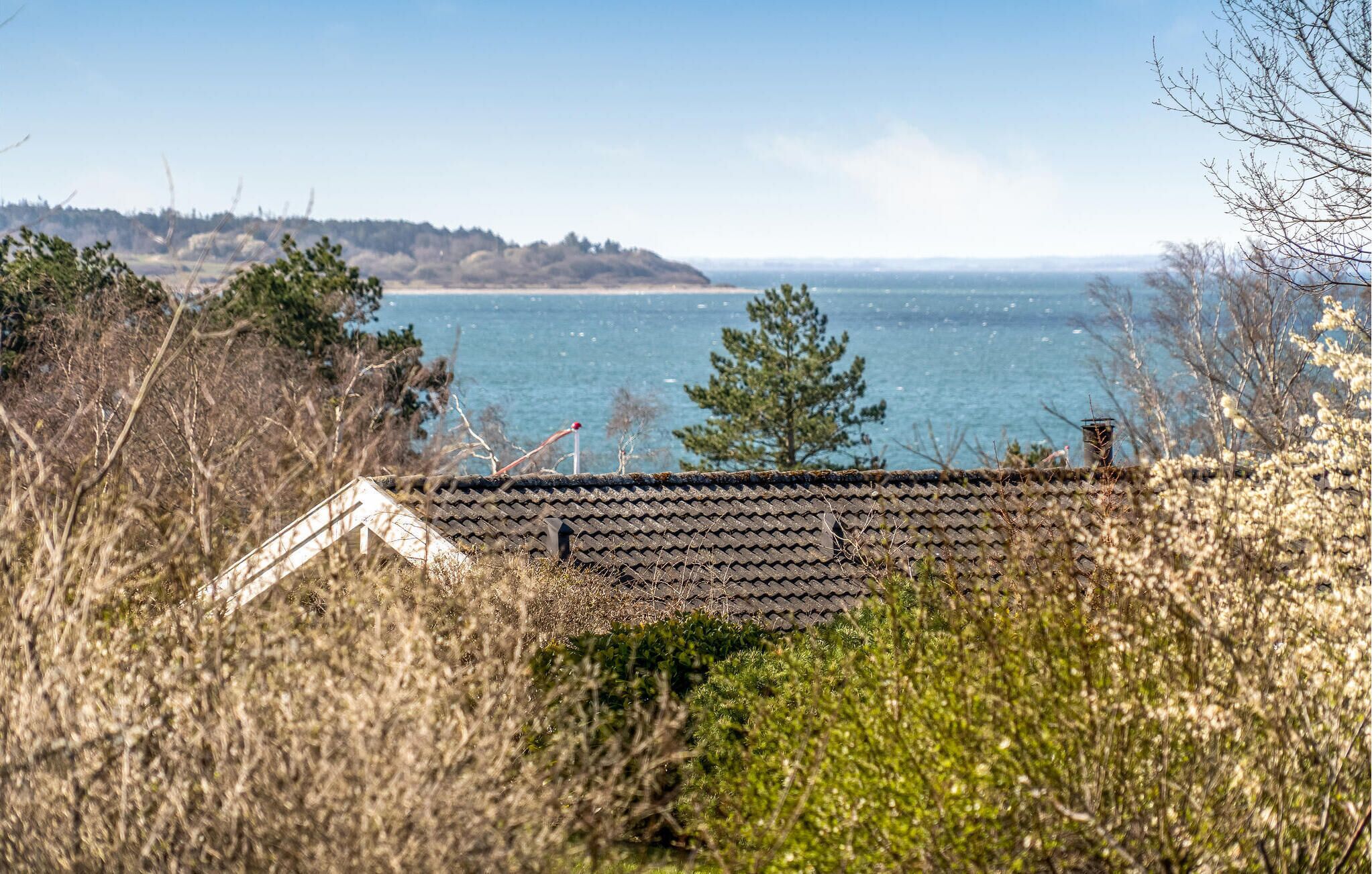 Vista costeira com uma casa de frente para o mar, rodeada por vegetação.