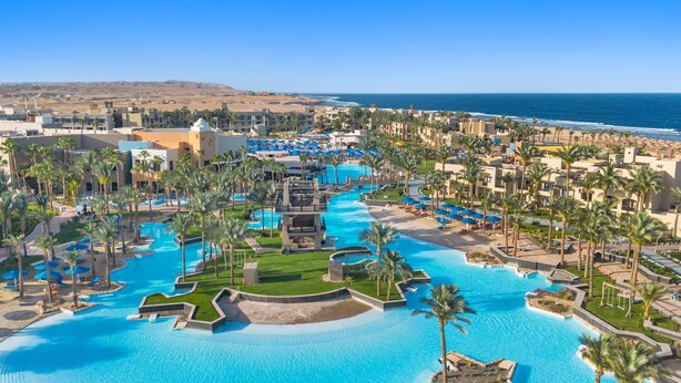 A resort with multiple swimming pools, palm trees, and a view of the ocean. - Pickalbatros The Palace Port Ghalib (El Quseir)