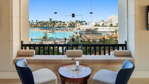 A balcony with a view of a pool and beach area, including lounge chairs and a small table with a candle. - Pickalbatros The Palace Port Ghalib (El Quseir)