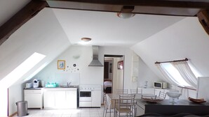 Een kleine keuken met een eethoek, een bank en een raam met gordijnen.