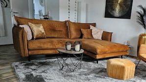 A living room with a brown sofa, a round coffee table, and a small ottoman. - Lounge 4 - stylish apartment 51sqm, fully equipped, air conditioning, parking at the house (Koblenz)