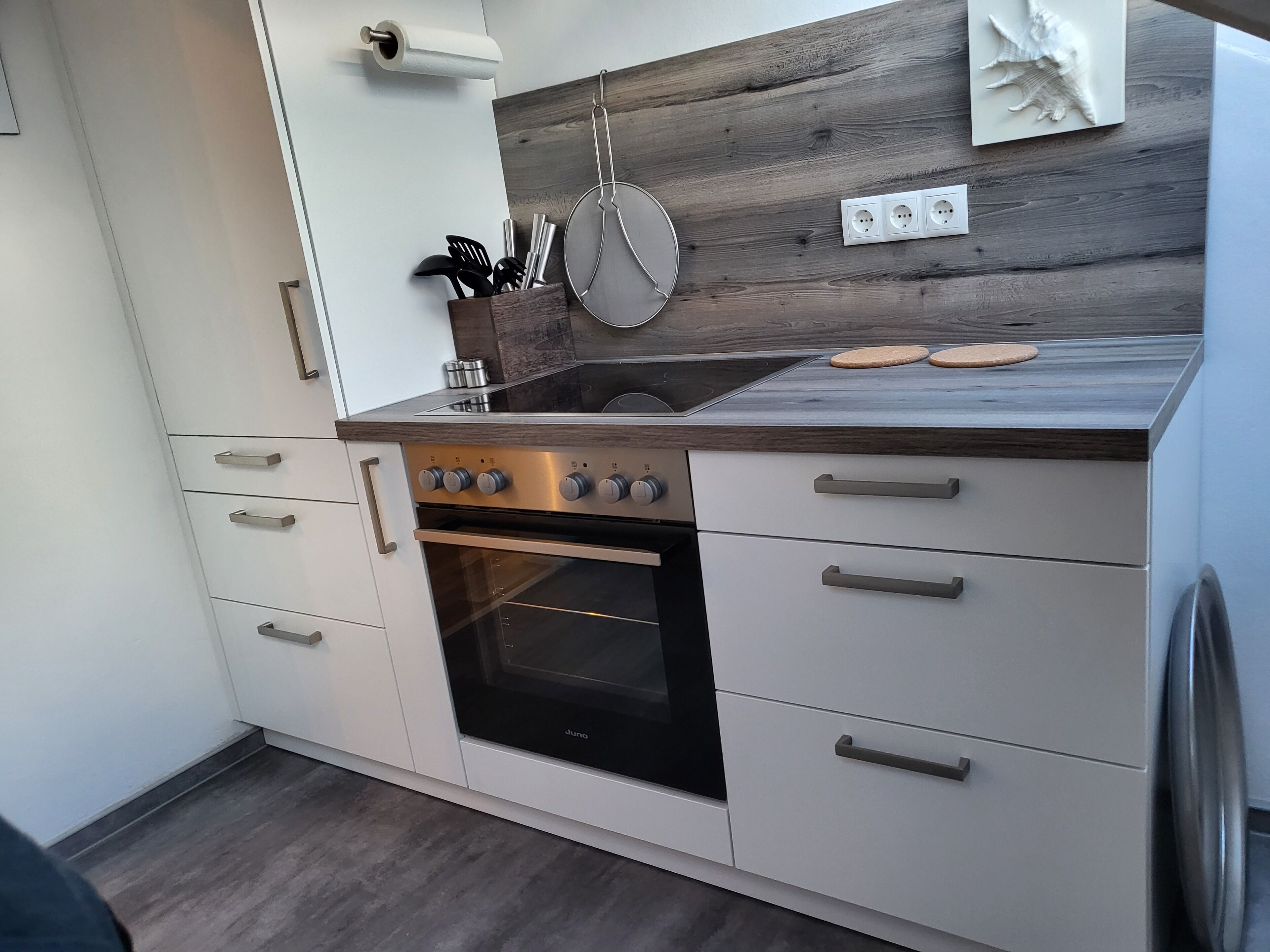 Une cuisine moderne avec un revêtement mural en bois, des appareils électroménagers en acier inoxydable et des meubles de cuisine blancs.