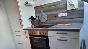 A modern kitchen with a wooden backsplash, stainless steel appliances, and white cabinetry. - Lounge 4 - stylish apartment 51sqm, fully equipped, air conditioning, parking at the house (Koblenz)