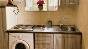 A compact kitchen with a built-in washer, a sink, and a window with a view of greenery. - Romantic cottage in the historic center of Collepardo (Collepardo)
