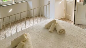 A bedroom with a bed, a window with open shutters, and a door with a shutter. - Romantic cottage in the historic center of Collepardo (Collepardo)
