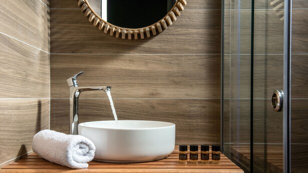 A bathroom with a wooden vanity, a white sink, and a towel. - Kipos Suites (Heraklion)