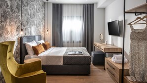 A modern bedroom with a bed, a bedside table, a TV, and a wardrobe. - Kipos Suites (Heraklion)