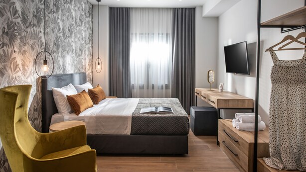 Een moderne slaapkamer met een bed, nachtkastje, televisie en kledingkast.