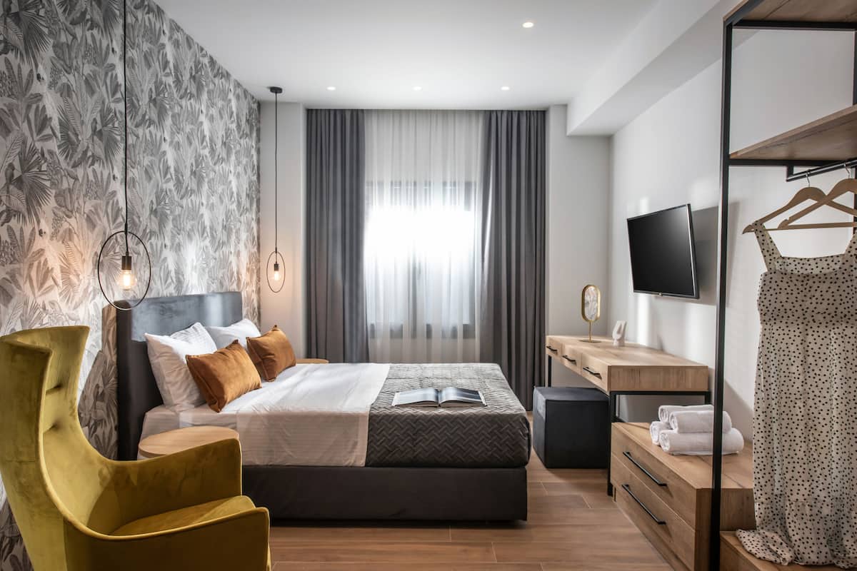 Een moderne slaapkamer met een bed, nachtkastje, televisie en kledingkast.