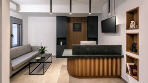 Een moderne receptie met een houten balie, een flatscreen televisie, een bank en een salontafel.
