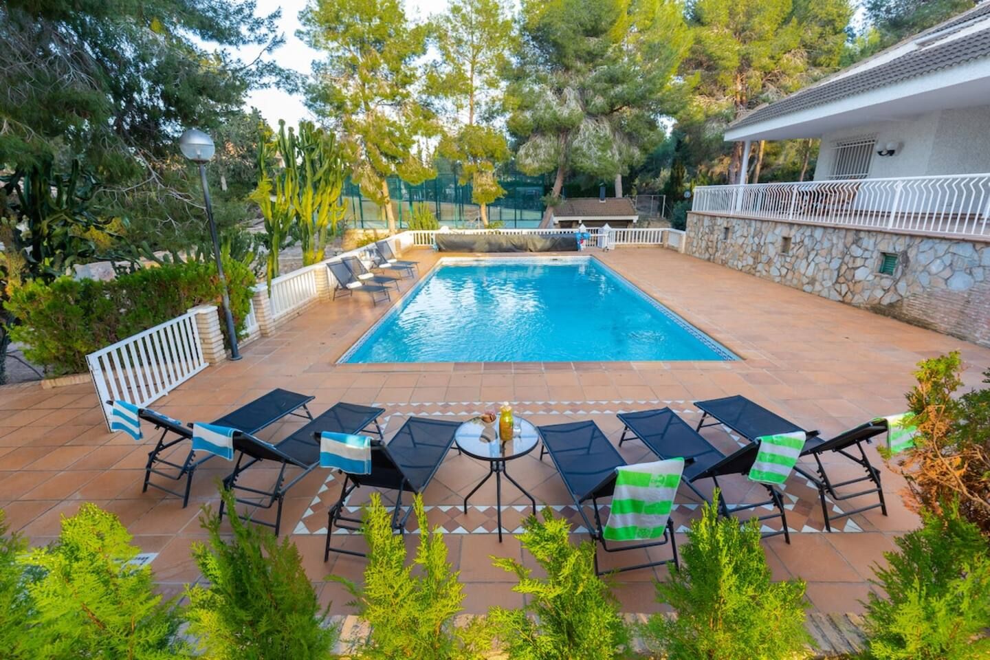 A swimming pool with lounge chairs and a stone wall.