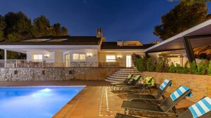 A swimming pool with lounge chairs and a stone wall. - Fidalsa Paradise Pines (La Alcayna)
