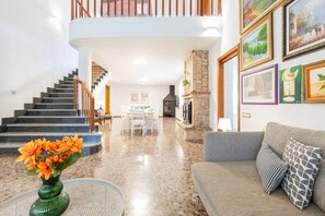 A spacious living area with a staircase, a dining table, and a sofa.