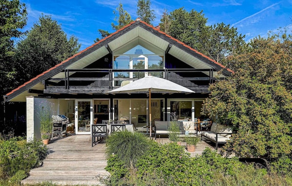 A two-story house with a balcony, a covered patio, and a wooden deck.